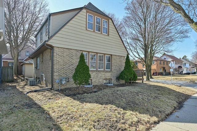 view of home's exterior with brick siding, central air condition unit, and a residential view