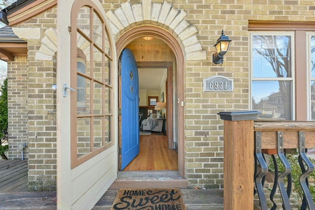 entrance to property featuring brick siding and roof with shingles