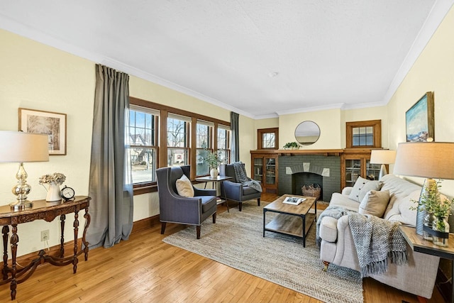 living room featuring light wood-type flooring, baseboards, a brick fireplace, and ornamental molding