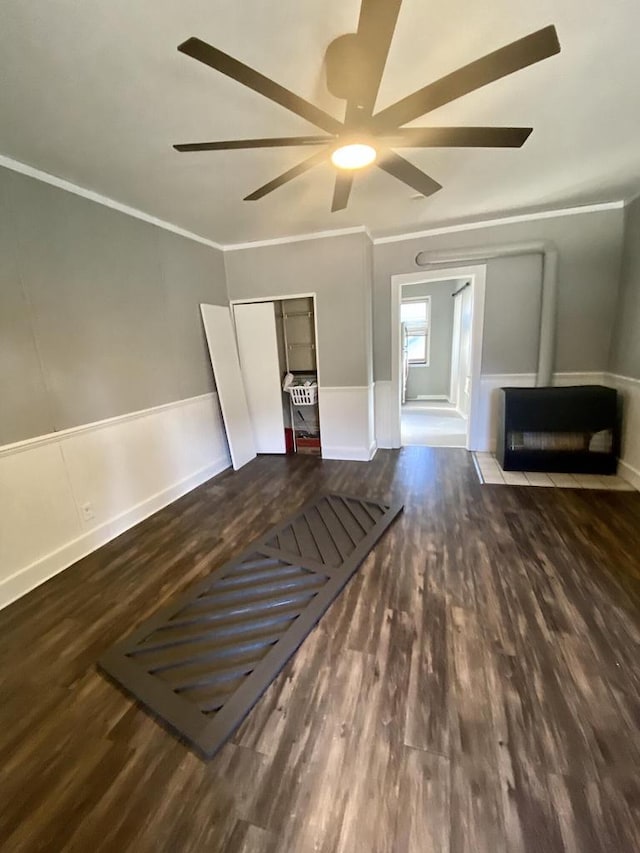 interior space featuring a wainscoted wall, ceiling fan, wood finished floors, crown molding, and a decorative wall