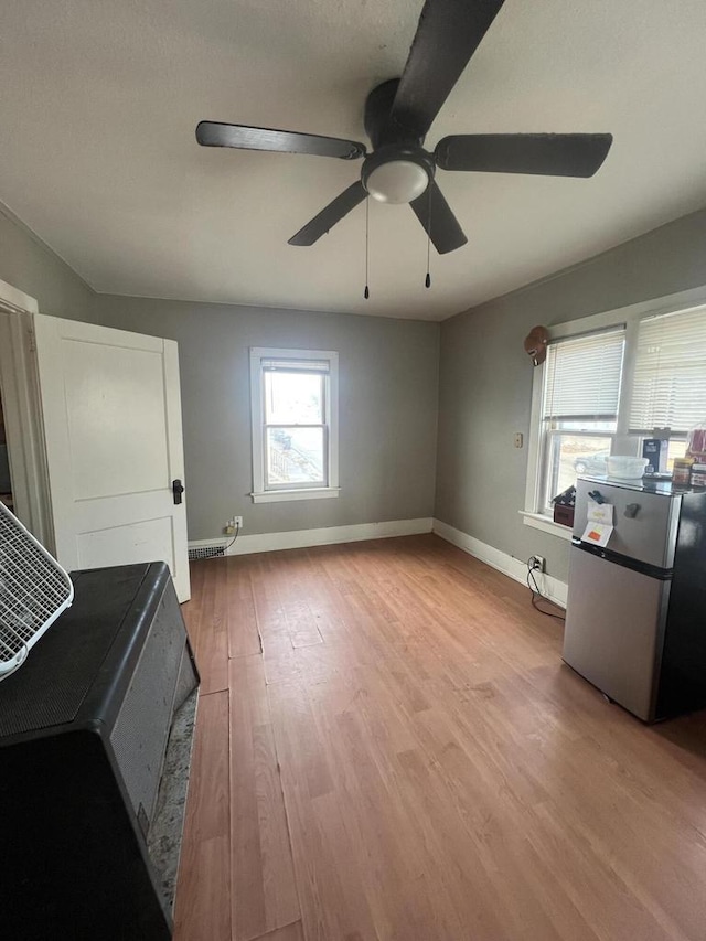 interior space featuring light wood finished floors, a ceiling fan, and baseboards