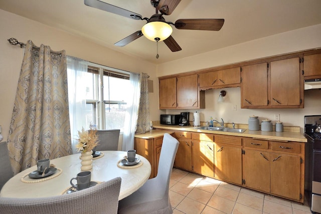 kitchen with light countertops, a sink, under cabinet range hood, and gas range