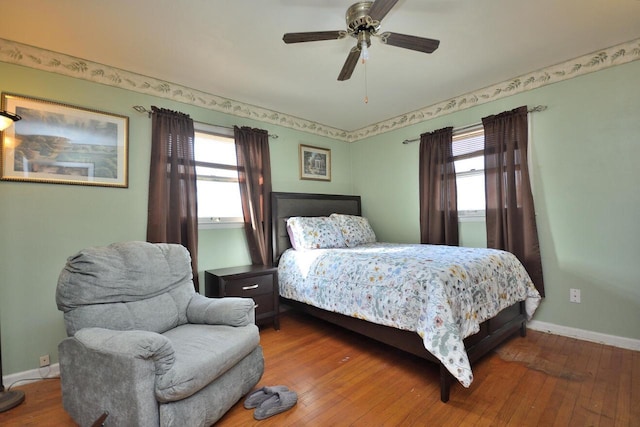 bedroom with baseboards, multiple windows, ceiling fan, and hardwood / wood-style floors