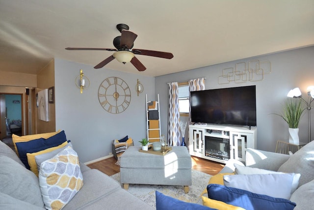 living room featuring ceiling fan, wood finished floors, and baseboards