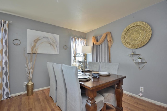 dining space featuring baseboards and wood finished floors