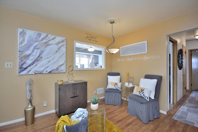 living area with baseboards, visible vents, and wood finished floors