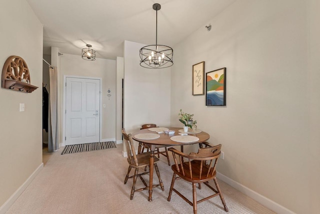 dining room featuring light carpet, an inviting chandelier, and baseboards