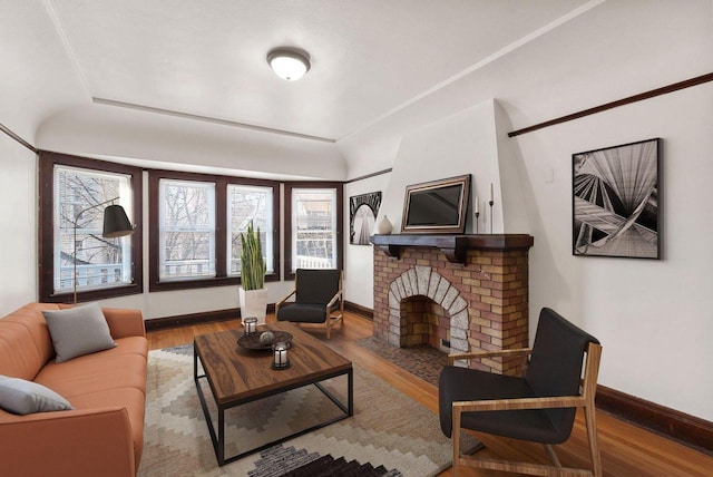 living area with a fireplace, wood finished floors, and baseboards