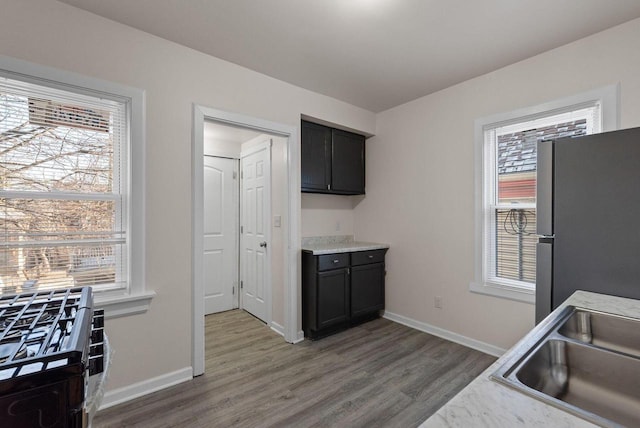 kitchen featuring wood finished floors, a sink, baseboards, light countertops, and freestanding refrigerator