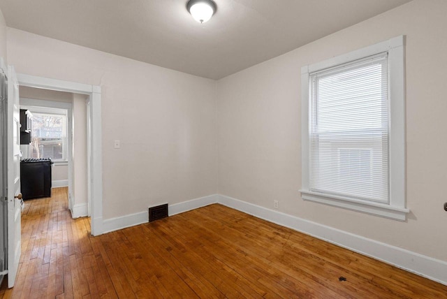 spare room with baseboards, visible vents, and hardwood / wood-style floors