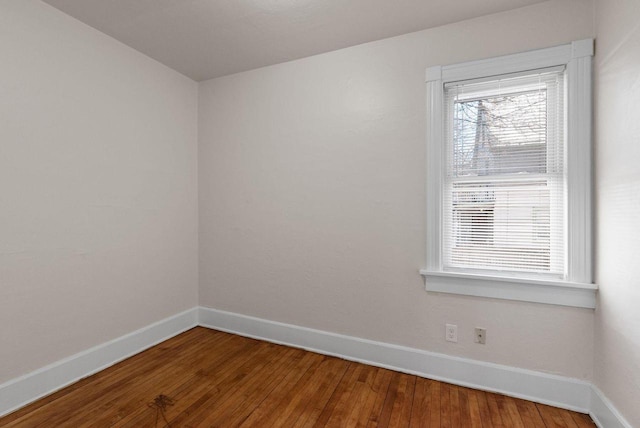 spare room featuring wood-type flooring and baseboards