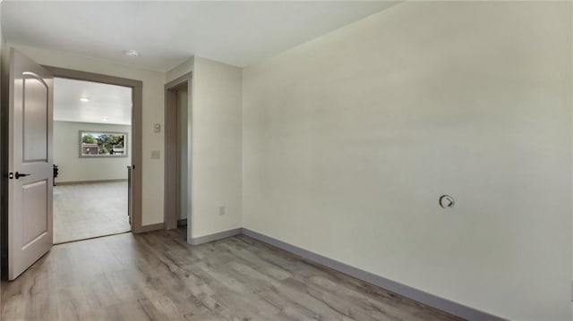 spare room featuring light wood-type flooring and baseboards