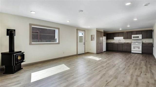 interior space featuring baseboards, recessed lighting, a wood stove, and light wood-style floors