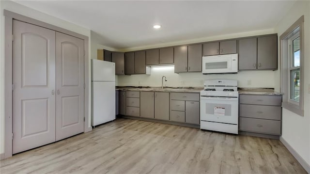 kitchen with white appliances, gray cabinets, light wood-style flooring, and baseboards