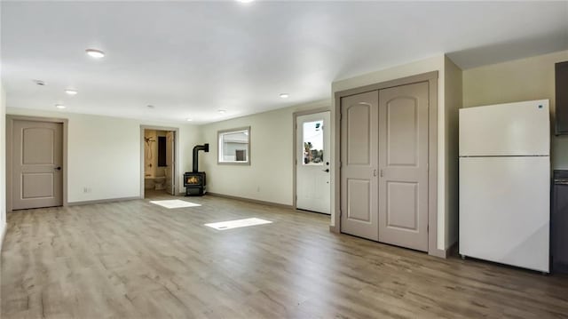 interior space featuring a wood stove, baseboards, and wood finished floors