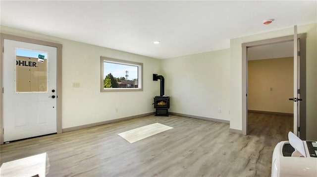 entryway featuring a wood stove, baseboards, and light wood finished floors