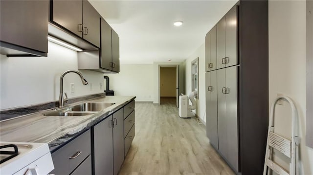 kitchen featuring baseboards, light countertops, a sink, and light wood-style floors