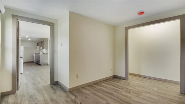 spare room with light wood-type flooring and baseboards