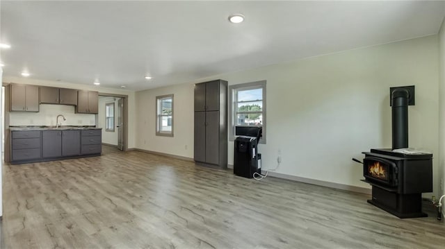 unfurnished living room with recessed lighting, baseboards, a sink, and light wood finished floors