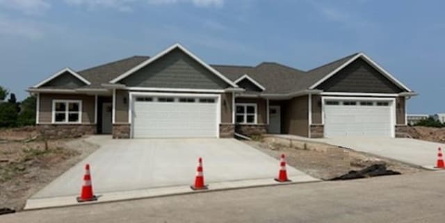 craftsman-style home with a garage, stone siding, and concrete driveway