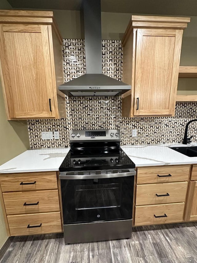kitchen featuring stainless steel electric stove, backsplash, light brown cabinets, a sink, and wall chimney exhaust hood