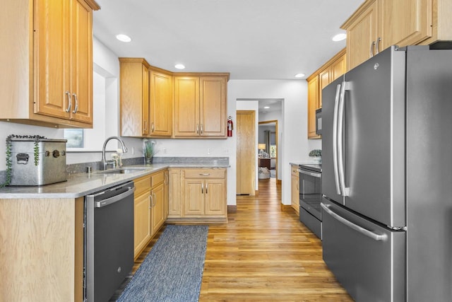 kitchen featuring stainless steel appliances, recessed lighting, light countertops, a sink, and light wood-type flooring