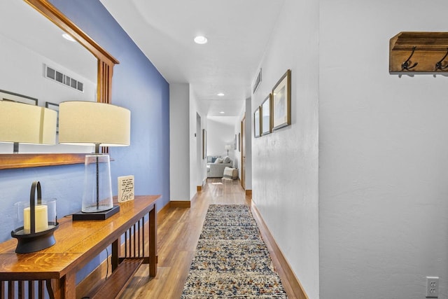 hallway featuring baseboards, visible vents, wood finished floors, and recessed lighting