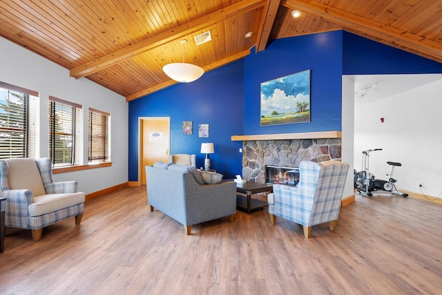 living area with a fireplace, baseboards, beam ceiling, and wood finished floors