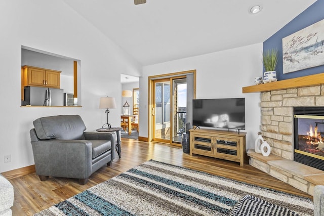 living room with a fireplace, vaulted ceiling, baseboards, and wood finished floors