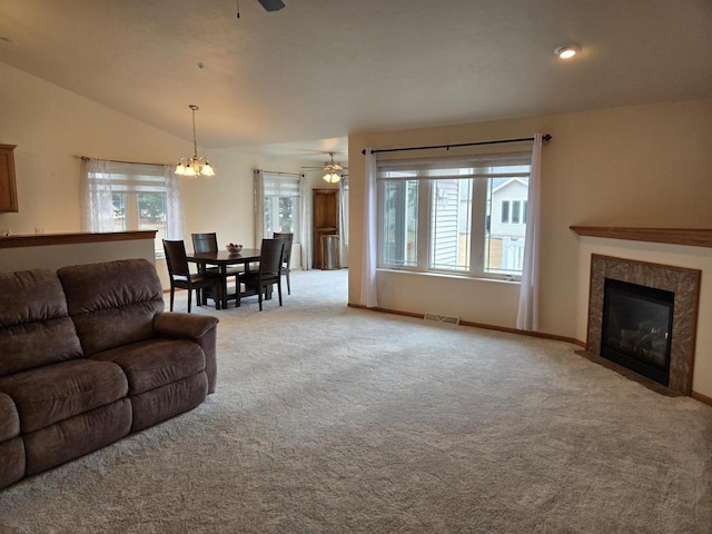 living room with a healthy amount of sunlight, visible vents, vaulted ceiling, and ceiling fan with notable chandelier