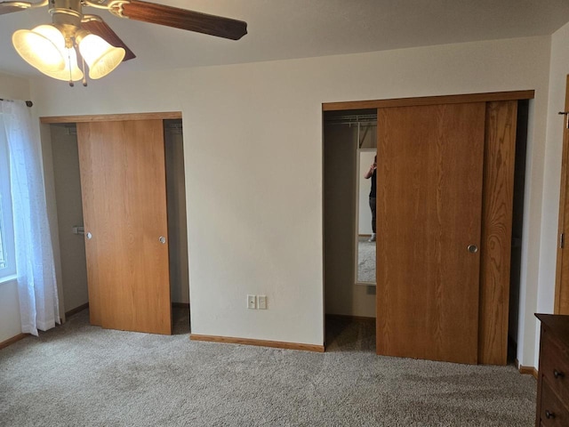 unfurnished bedroom featuring carpet floors, ceiling fan, baseboards, and multiple closets