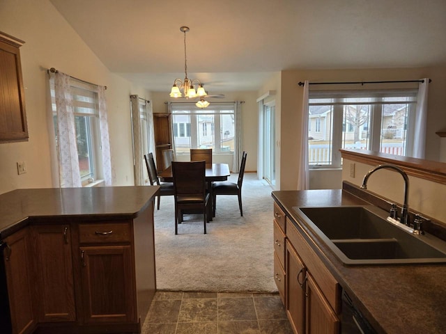 kitchen featuring a notable chandelier, dark countertops, lofted ceiling, dark carpet, and a sink