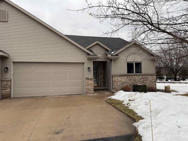 single story home featuring concrete driveway, brick siding, and a shingled roof