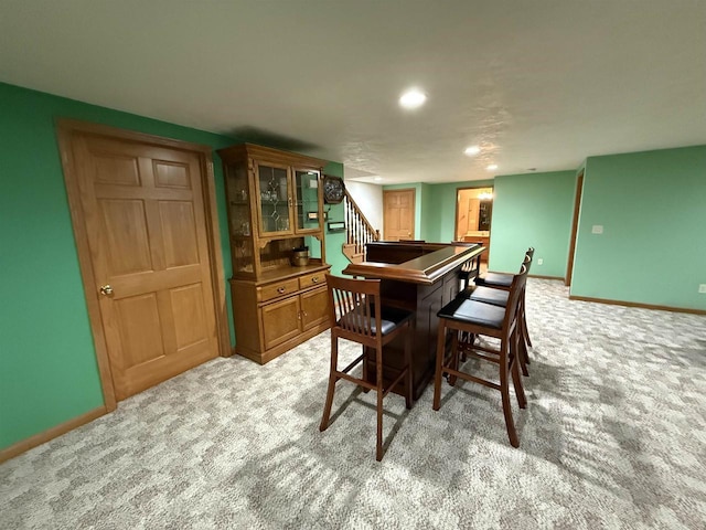 dining area featuring stairs, baseboards, and light colored carpet