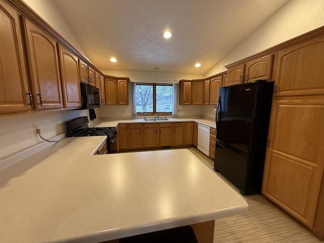 kitchen featuring black appliances, light countertops, a sink, and recessed lighting