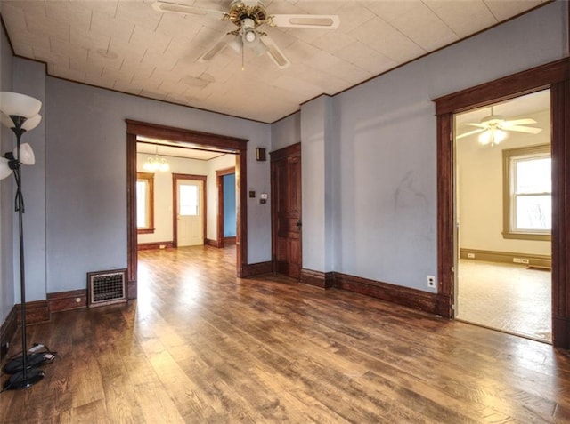 empty room with visible vents, ceiling fan, baseboards, and wood finished floors