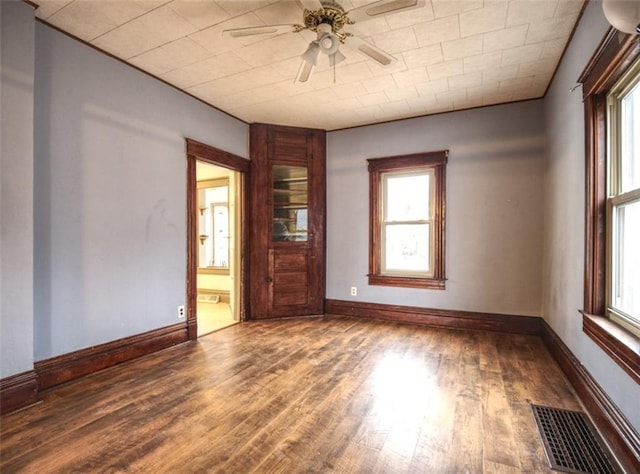 spare room featuring visible vents, ceiling fan, baseboards, and wood finished floors