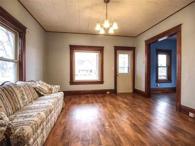 unfurnished living room featuring wood-type flooring, a wealth of natural light, and an inviting chandelier