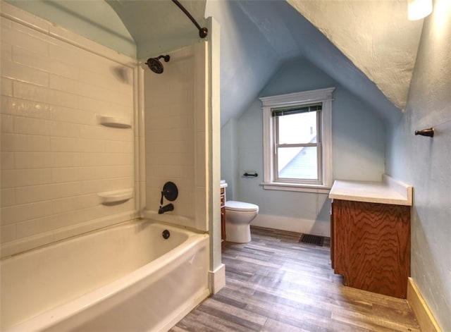 full bathroom with shower / washtub combination, toilet, vaulted ceiling, wood finished floors, and baseboards