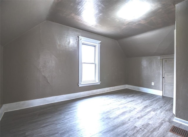 bonus room with lofted ceiling, visible vents, baseboards, and wood finished floors