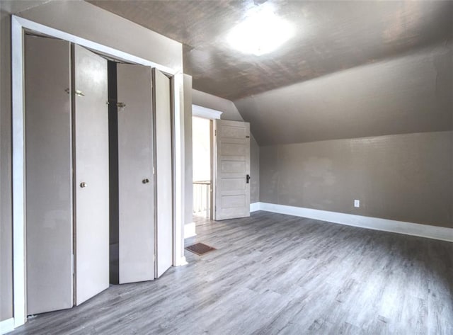 additional living space featuring visible vents, baseboards, vaulted ceiling, and wood finished floors