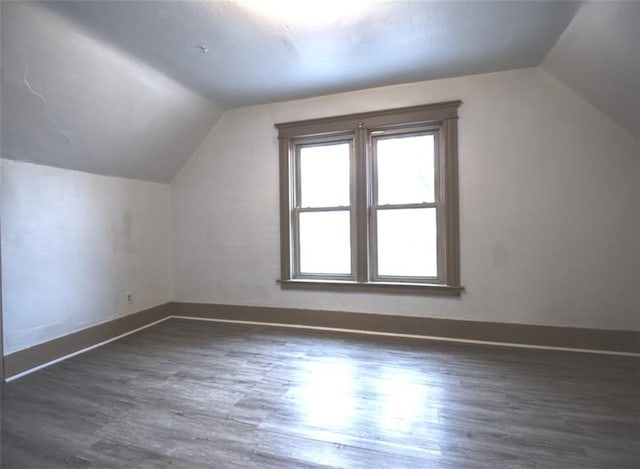 bonus room with vaulted ceiling, wood finished floors, and baseboards