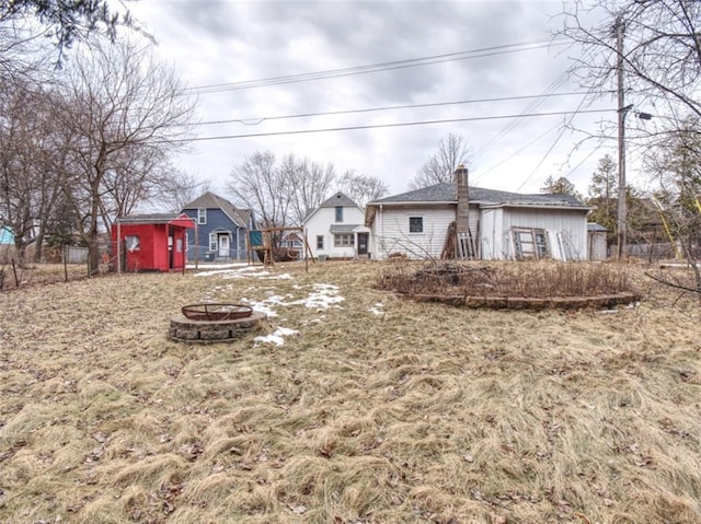 view of yard featuring an outdoor fire pit, fence, an outbuilding, and a shed