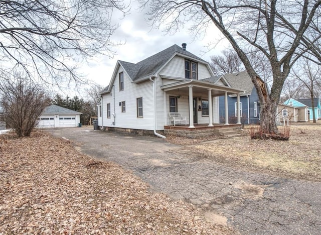 view of front of house featuring a shingled roof, an outbuilding, covered porch, and a detached garage