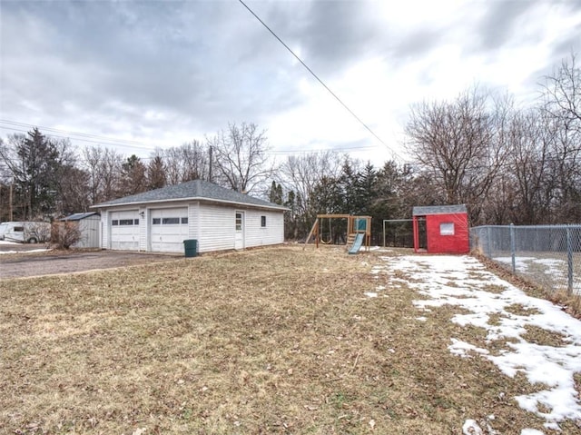 view of yard featuring an outbuilding, a playground, fence, and a detached garage