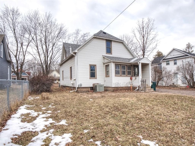 view of front facade featuring central AC unit, fence, and roof with shingles