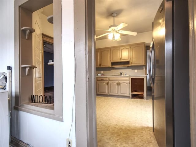 kitchen with a ceiling fan, freestanding refrigerator, light countertops, and a sink