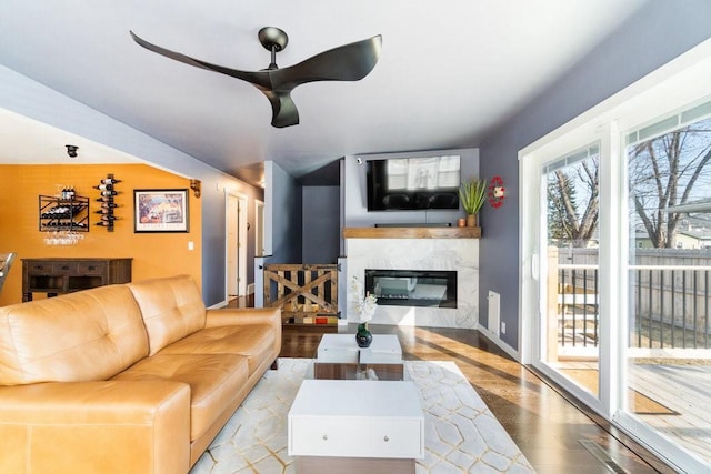 living area featuring ceiling fan, baseboards, wood finished floors, and a high end fireplace