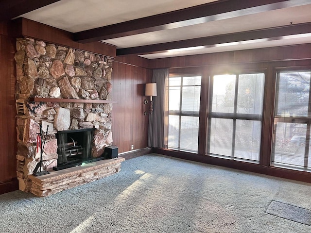 unfurnished living room with beamed ceiling, carpet, a fireplace, and a healthy amount of sunlight