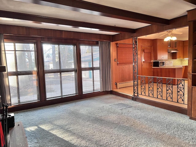 carpeted empty room with wooden walls, a baseboard heating unit, and beamed ceiling